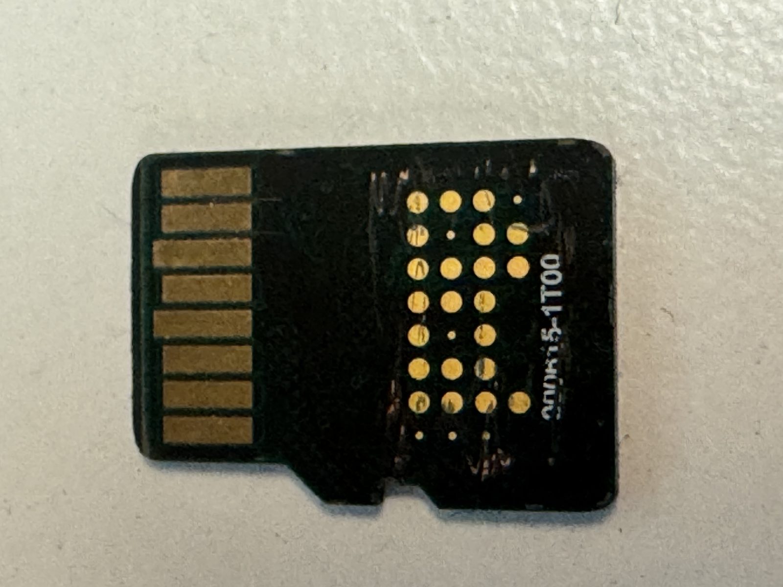 Back of the monolithic microSD card with the moulding removed to expose the grid of gold technical test pads used to read the NAND directly